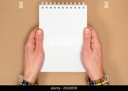 Mains tenant un cahier en spirale avec des feuilles vierges pour les écrits Banque D'Images