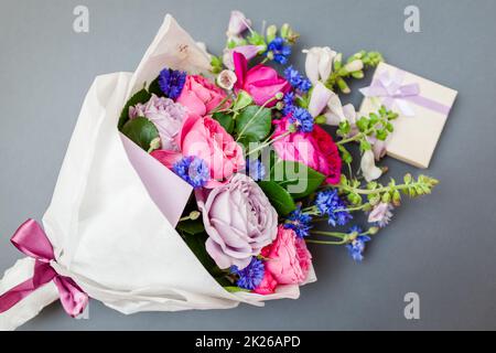 Gros plan du bouquet de roses foxgants boutons de baccalauréat fleurs enveloppées dans du papier avec boîte cadeau. Cadeau de vacances Banque D'Images