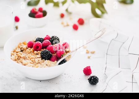 Bol petit déjeuner avec granola, muesli, framboise, mûre sur table grise Banque D'Images