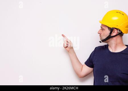 Travailleur d'interprétation derrière un fond blanc. Port d'un masque vert et d'un casque jaune Banque D'Images