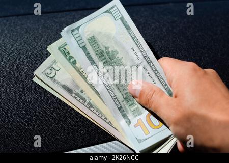 l'homme remet de l'argent dans une voiture. Une main de dollars. Banque D'Images