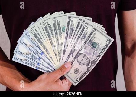 les dollars sont détenus par un fan par un homme dans sa main. Dollar américain. Banque D'Images