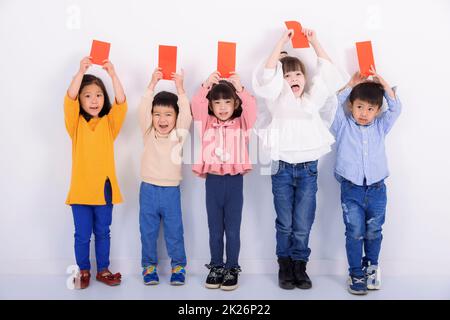 Bonne année chinoise. Des enfants enthousiastes montrant des enveloppes rouges pour la chance Banque D'Images