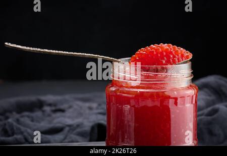 caviar rouge granuleux frais dans un pot en verre sur une table en bois Banque D'Images