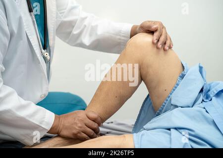Médecin asiatique physiothérapeute examinant, massant et traitement genou et jambe d'un patient senior dans la clinique orthopédique infirmière hôpital. Banque D'Images