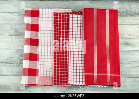 Vue de dessus d'un ensemble vide de tissus de cuisine rouges et blancs à carreaux et à rayures, de textile, de nappe ou de serviette sur une table rustique en bois clair. Modèle pour montage d'affichage de produit. Banque D'Images