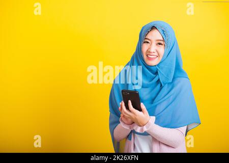 Asiatique musulmane arabe femme Islam porter hijab sourire elle en utilisant tenir le smartphone mobile Banque D'Images