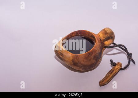 tasse en bois sculpté nommée kuksa avec un café frais sur fond gris Banque D'Images