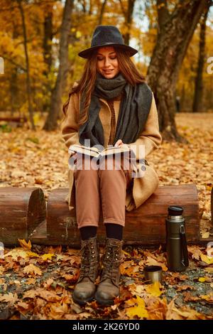 La femme reste lire le livre dans la forêt d'automne Banque D'Images