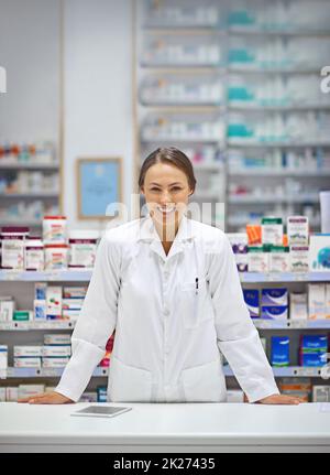 Fournir des ordonnances et un sourire.Portrait d'un jeune pharmacien attrayant debout au comptoir d'ordonnance. Banque D'Images