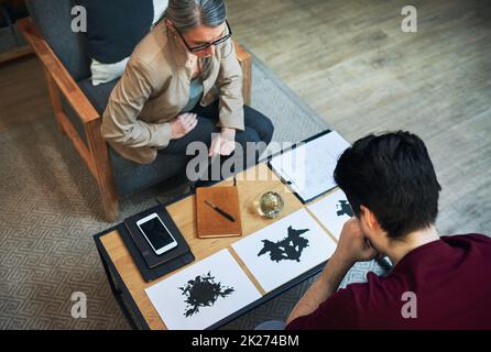 Une façon de scanner le subconscient.Prise de vue d'un psychologue mature effectuant un test d'inkblot avec sa patiente pendant une séance thérapeutique. Banque D'Images