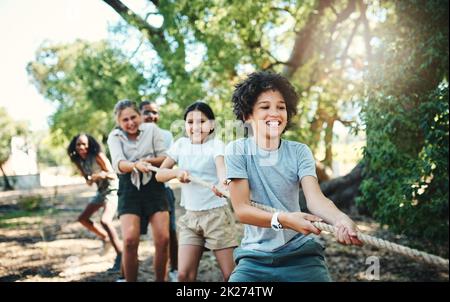 Tirez une équipe plus dure.Prise de vue d'un groupe d'adolescents jouant un jeu de remorqueurs de guerre au camp d'été. Banque D'Images