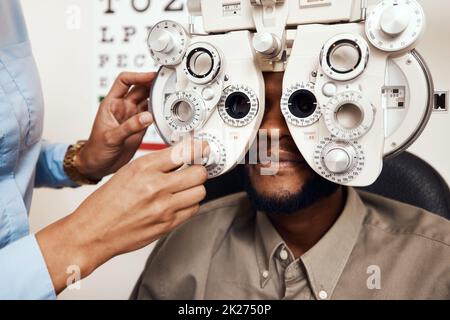 Ce qui est mieux 1 ou 2.Cliché d'un optométriste examinant les yeux de son patient avec un réfracteur optique. Banque D'Images