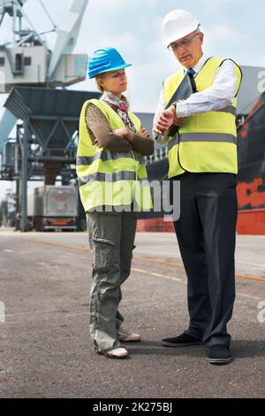 Le temps est de l'essence.Deux ingénieurs discutent de la planification sur un site lorsqu'ils se trouvent dans le chantier naval. Banque D'Images