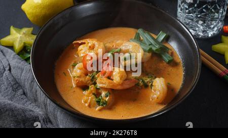 Crevettes thaïlandaises au curry rouge.Soupe de curry rouge traditionnelle thaïlandaise avec crevettes et lait de coco.Curry Panaeng et arrière-plan sombre. Banque D'Images