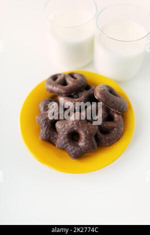 Les biscuits de pain d'épice enrobés de chocolat sont posés sur une assiette jaune avec un verre de lait. Place pour une inscription. Banque D'Images