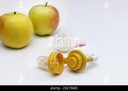 Grignoteuses avec pommes fraîches sur table blanche, gros plan. Alimentation bébé. Banque D'Images