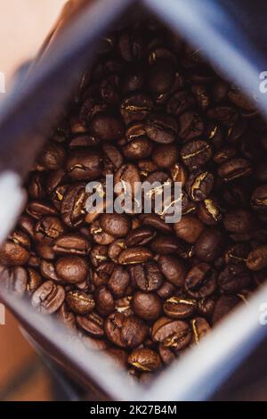 Grains de café dans un paquet d'une feuille de plastique sur fond de bois. Café aromatique rôti vue d'en haut. Banque D'Images