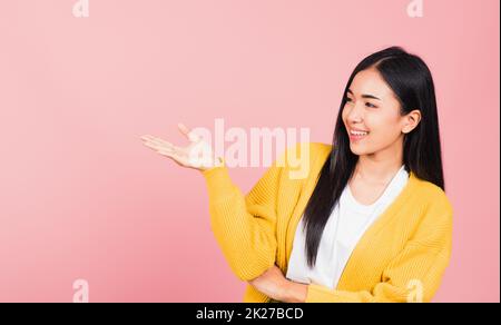 une femme sourit debout et présente le produit en tenant quelque chose sur le côté de la paume Banque D'Images