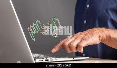 Homme travaillant avec un tableau de chandeliers sur un ordinateur portable. Analyse du marché boursier. Finance, investissement, concept commercial. Homme d'affaires analysant les mouvements de prix. Un index mâle sur le clavier. Photo de haute qualité Banque D'Images