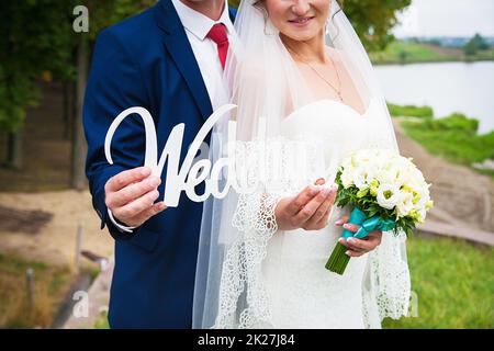 panneau en bois blanc entre les mains du mariage de la mariée et du marié Banque D'Images