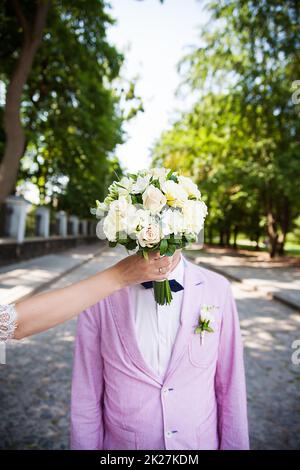 la mariée tenant un bouquet dans le visage du marié Banque D'Images