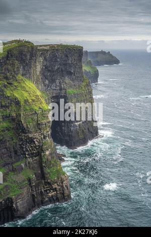 Touristes marchant sur les falaises de Moher avec tour de guet Moher Tour sur une distance, Irlande Banque D'Images