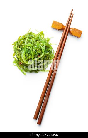 Wakame vert. Salade d'algues et baguettes isolées sur fond blanc. Banque D'Images