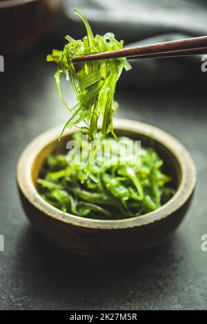 Wakame vert. Salade d'algues dans un bol sur table noire. Banque D'Images