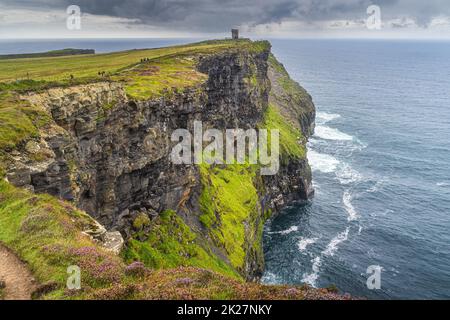 Touristes sur un sentier à la Tour Moher sur les falaises emblématiques de Moher, en Irlande Banque D'Images