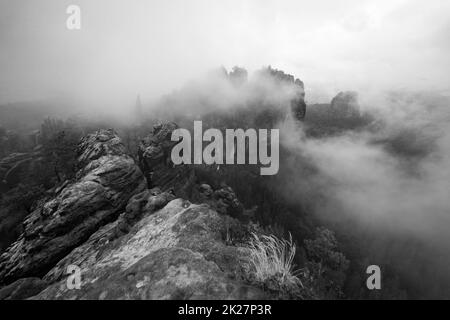 Un matin nuageux tôt en montagne. Schrammsteine - groupe de roches sont un long, strung-out, très déchiquetés dans les montagnes de grès d'Elbe situé en Suisse saxonne en Allemagne de l'est. Noir et blanc. Banque D'Images