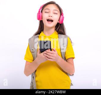 Bonne étudiante, jeune fille, qui écoute de la musique avec un casque et chante des chansons Banque D'Images