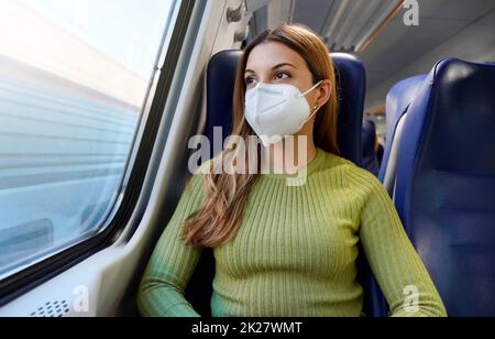 Jeune femme d'affaires portant un masque de protection assise détendue dans le train Banque D'Images