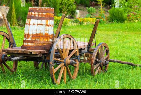 Ancien chariot en bois avec un fût sur l'herbe verte. Mise au point sélective Banque D'Images