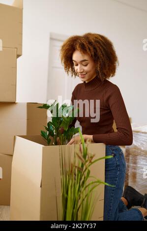 Jeune femme emballant la fleur pendant la journée de déménagement Banque D'Images