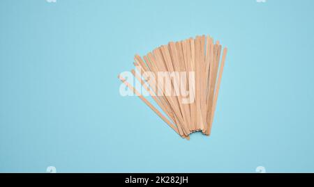 bâtonnets jetables en bois pour mélanger les boissons chaudes sur fond bleu.Cuillère à café et à thé, sans gaspillage Banque D'Images