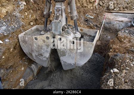 Le béton liquide est versé dans une fondation à l'aide d'une pince Banque D'Images