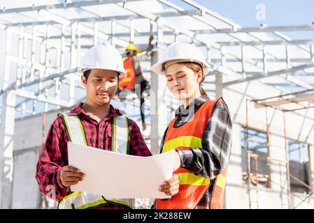 Deux architectes et clients discutant aider à créer un plan avec le projet de construction de maison sur le site de construction Banque D'Images