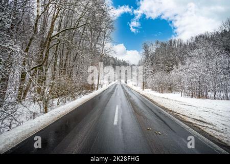 route asphaltée en hiver forêt enneigée, ciel bleu Banque D'Images