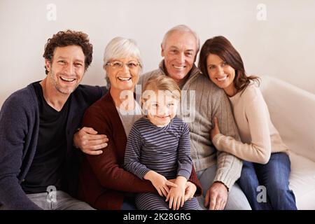 Une famille heureuse - ce que tout le monde pourrait vouloir de plus. Portrait court d'une famille de plusieurs générations heureuse assise ensemble sur un canapé Banque D'Images