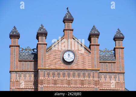 Horloge sur le mur d'un bâtiment en brique. Bâtiment en briques brunes avec boshni et heures. Banque D'Images