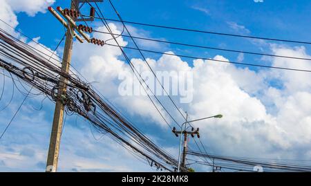 Chaos absolu de câble sur le mât de puissance thaïlandais bleu ciel de Thaïlande. Banque D'Images