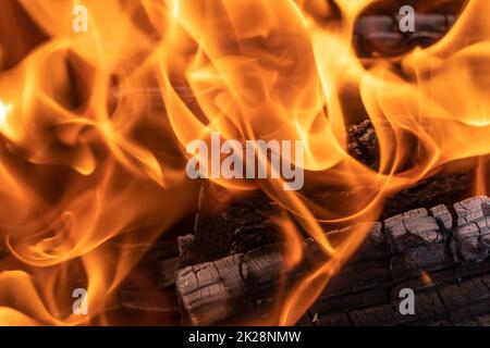 Un feu éclatant dans l'obscurité. Allumage du bois dans le feu. Une flamme vive. Étincelles et flammes dans l'obscurité. Chaleur incandescente et charbons et flammes.Un feu de joie flamboyant. Banque D'Images