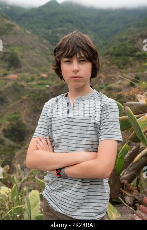 Portrait d'un adolescent dans un polo sur fond de montagnes. Banque D'Images