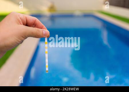 Hand with measuring pool strips to check water quality in a swimming pool Banque D'Images
