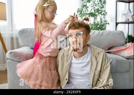 La fille crée une coiffure drôle pour le père Banque D'Images