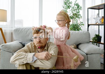 Mignonne fille faisant la coiffure pour le père épuisé Banque D'Images