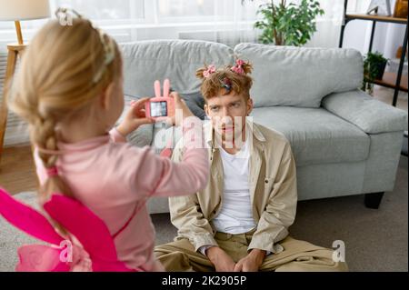 Fille faisant une photo de père avec maquillage drôle Banque D'Images