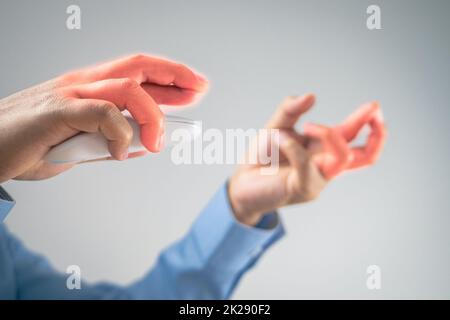 L'homme utilise une souris jusqu'à ce que ses doigts douleurs. Concept de syndrome de bureau. La zone des symptômes de douleur est indiquée en rouge. Gros plan moyen avec un peu d'espace de copie. Banque D'Images