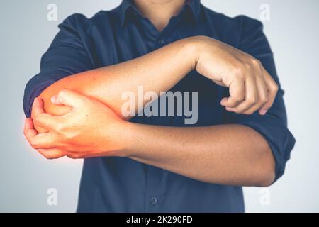 Blessure au coude due au tennis et au golf. L'homme tient son bras. La zone des symptômes de douleur est indiquée en rouge. Connaissance des soins de santé. Gros plan moyen. Banque D'Images